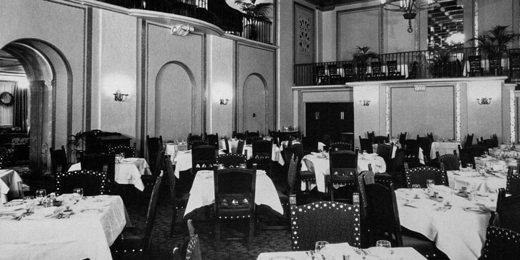 A restaurant with tables and chairs set up for dinner.